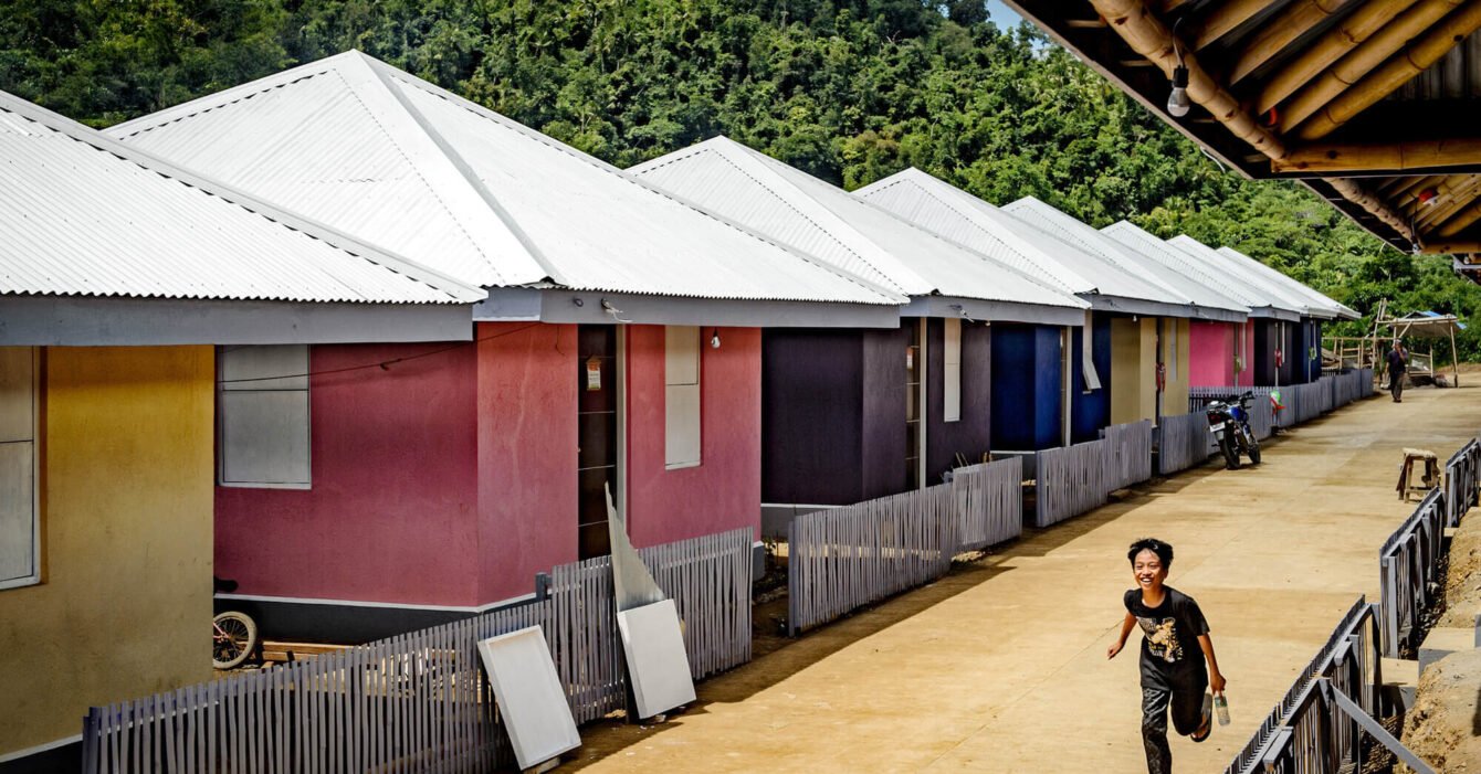 A boy runss along a vibrant path lined with colorful houses, showcasing Affordable Housing Philippines phenomenon.