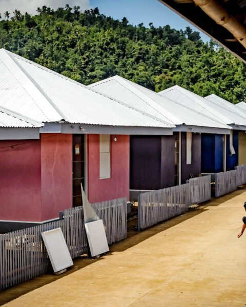 A boy runss along a vibrant path lined with colorful houses, showcasing Affordable Housing Philippines phenomenon.