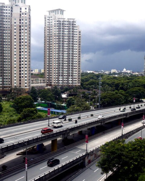 Commercial and residential buildings along a flyover or skyway over a major thoroughfare in Metro Manila, Philippines.