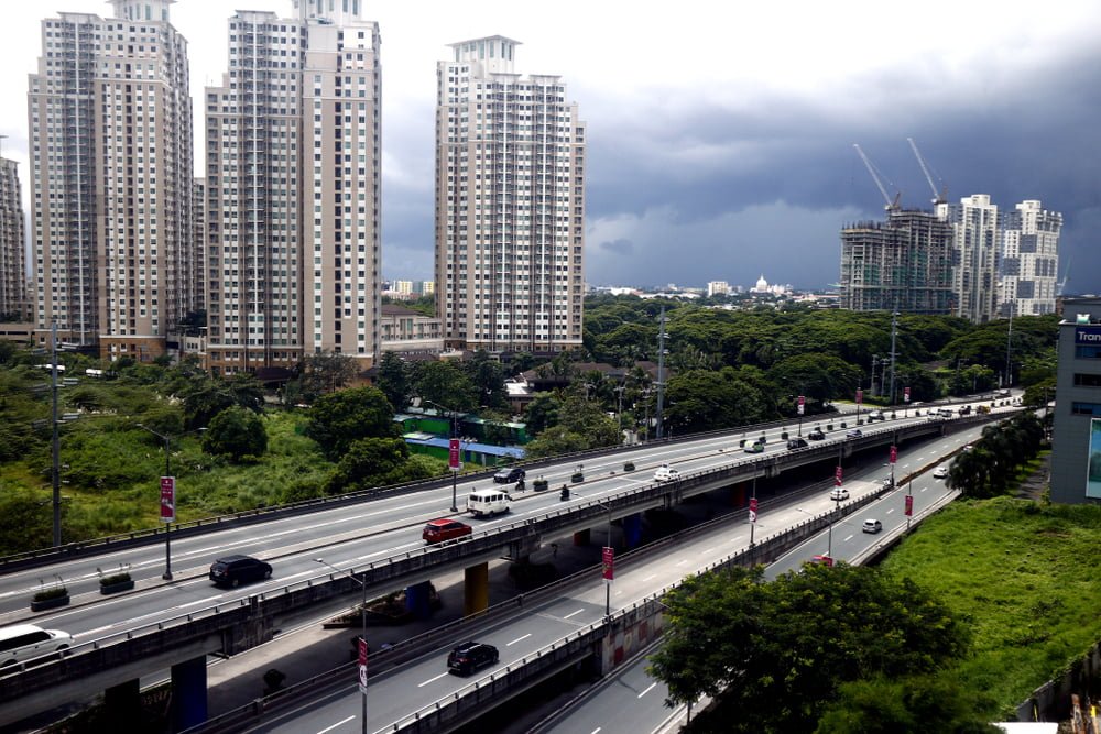 Commercial and residential buildings along a flyover or skyway over a major thoroughfare in Metro Manila, Philippines.