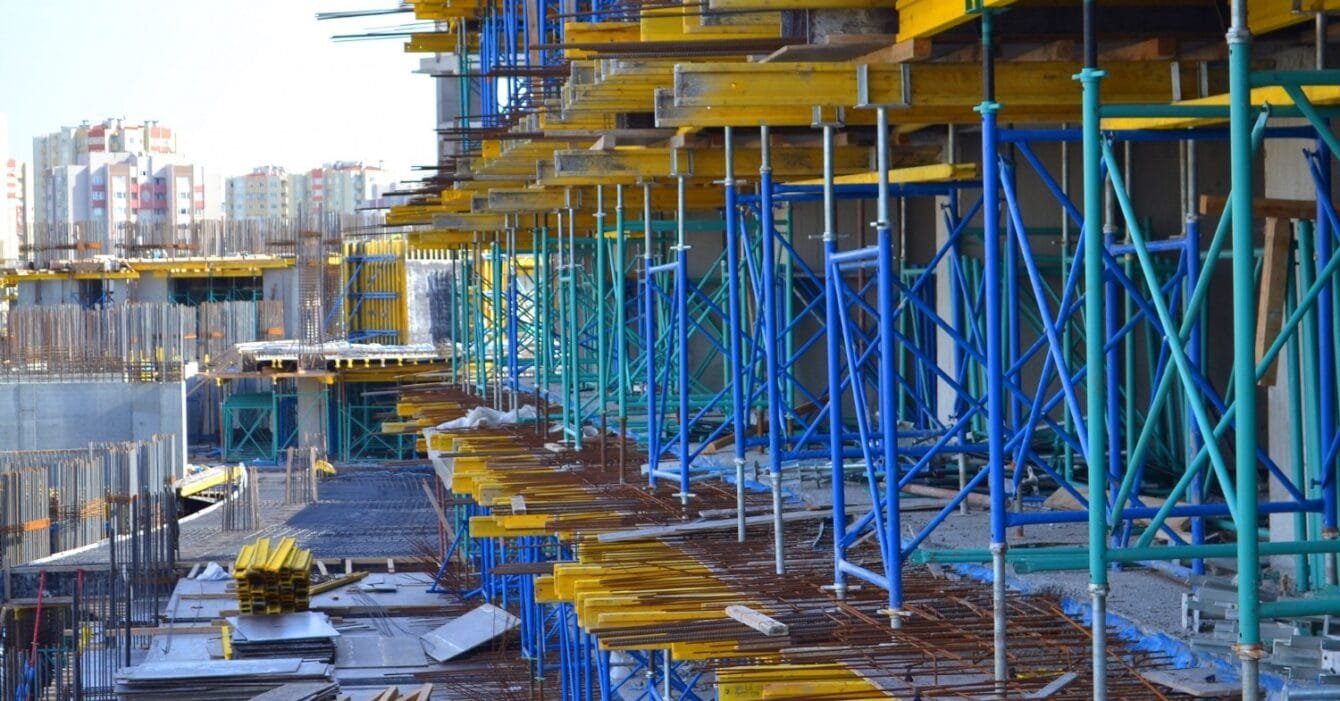 Construction Safety Standards Philippines: Construction site with colorful scaffolding and building materials, with cityscape in the background.