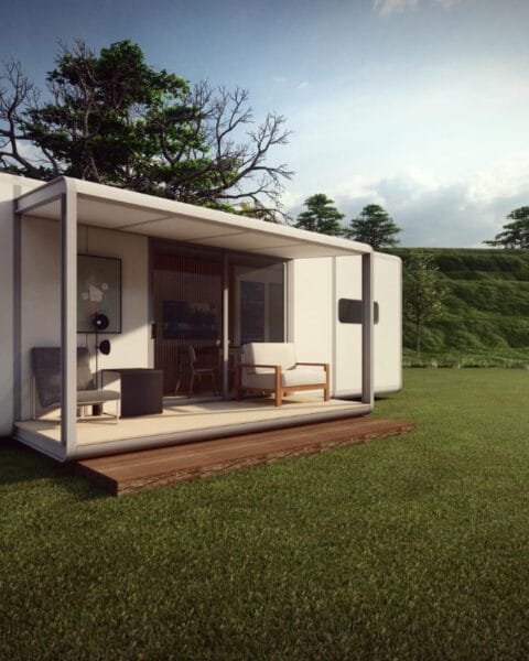 An example of Modular Construction in the Philippines: a modern small house with large windows in a grassy landscape near a tree line.