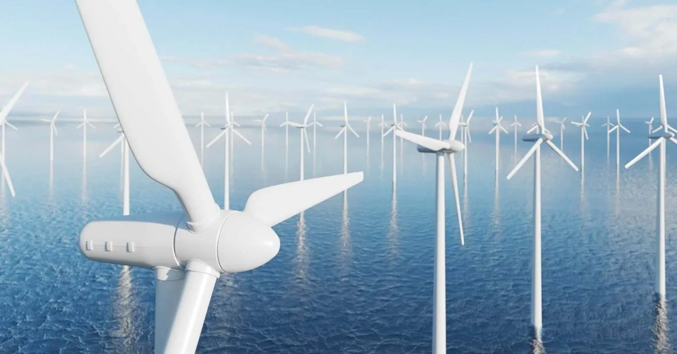 2148907403 Philippines Offshore Wind Energy: A close-up of a white wind turbine blade against a backdrop of multiple offshore wind turbines in a calm sea under a blue sky.