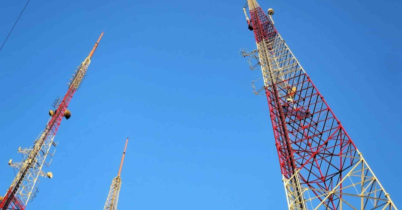 Philippines Telecom Infrastructure: Three towering communication antennas against a clear blue sky, showcasing red and white structural design elements.