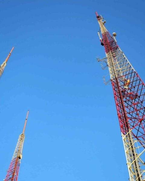 Philippines Telecom Infrastructure: Three towering communication antennas against a clear blue sky, showcasing red and white structural design elements.