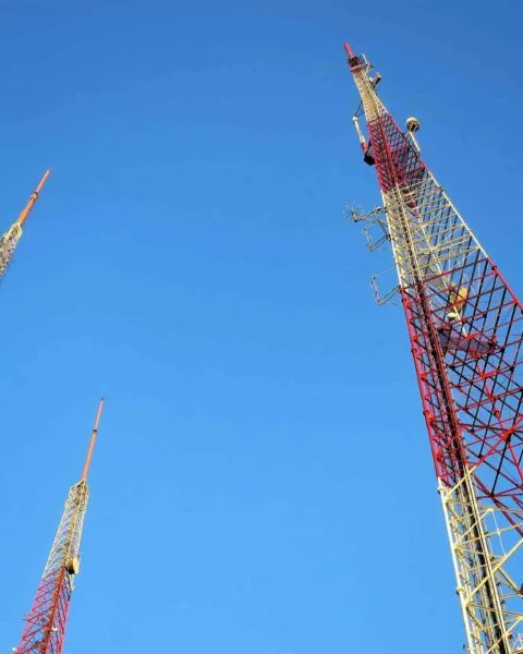 Philippines Telecom Infrastructure: Three towering communication antennas against a clear blue sky, showcasing red and white structural design elements.