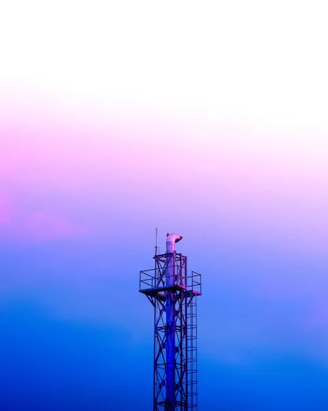 A tall communication tower against a gradient sky, transitioning from pink to blue, with crisp lines and a modern design, representing Philippines Telecom Tower Expansion.
