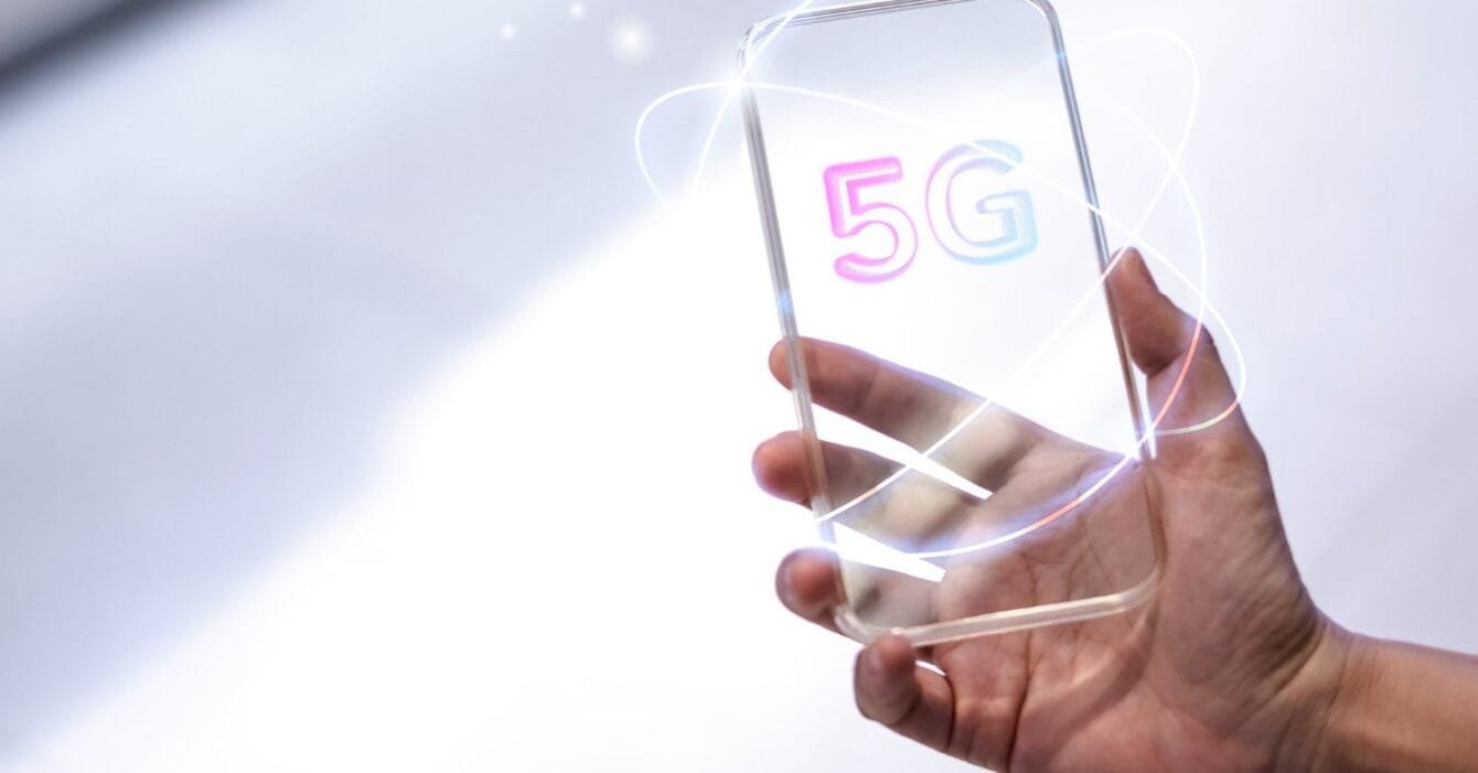Philippines 5G Rural Expansion: A hand holds a sleek, modern smartphone displaying a colorful "5G" logo, surrounded by glowing, dynamic lines.