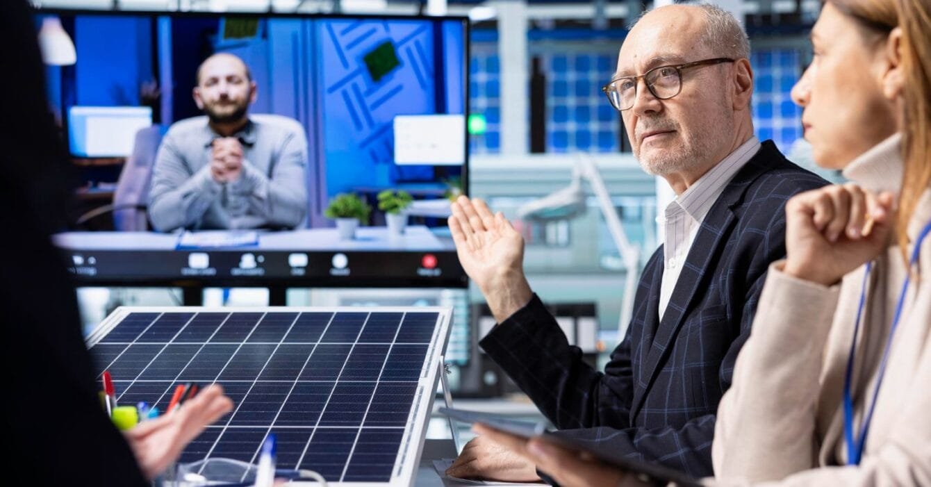 Philippines Renewable Energy Auctions: A group of professionals engaged in a video conference, discussing ideas while a solar panel model is displayed on the table.