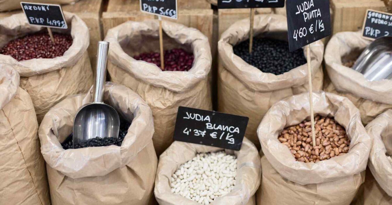 Philippines Agri & Commodity Surge: Display of various beans in paper bags, labeled with prices and types, including azuki, red, black, white, and pinto beans.