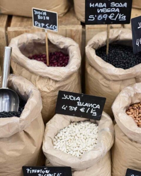Philippines Agri & Commodity Surge: Display of various beans in paper bags, labeled with prices and types, including azuki, red, black, white, and pinto beans.
