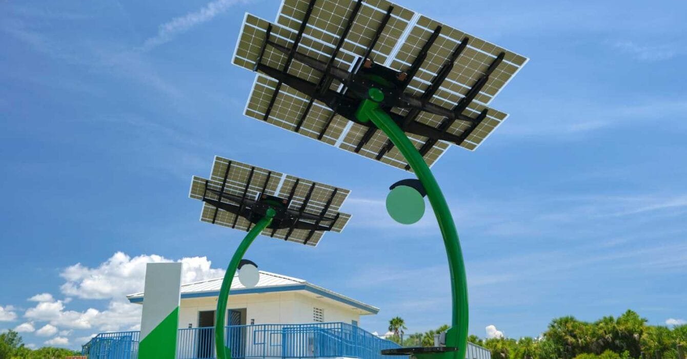 getty-images-8-0VfQfdbws-unsplash Philippines Renewable Energy Auction Reform: Two modern solar trees with photovoltaic panels stand in front of a white building, set against a bright blue sky.