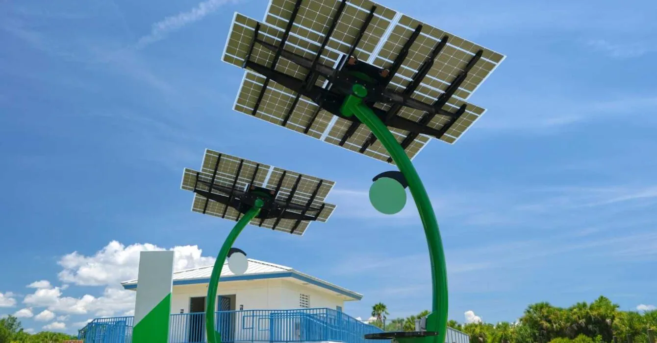 Philippines Renewable Energy Auction Reform: Two modern solar trees with photovoltaic panels stand in front of a white building, set against a bright blue sky.
