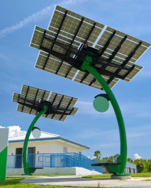 Philippines Renewable Energy Auction Reform: Two modern solar trees with photovoltaic panels stand in front of a white building, set against a bright blue sky.