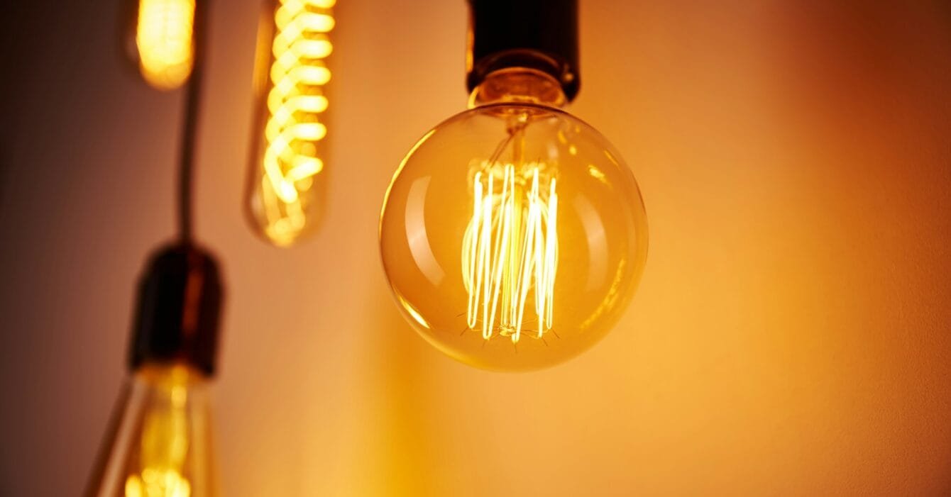 Philippines Energy Auction Reform: Three vintage light bulbs emit a warm glow, showcasing glowing filaments against a softly illuminated background.