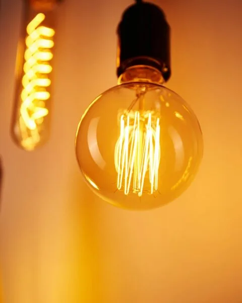 Philippines Energy Auction Reform: Three vintage light bulbs emit a warm glow, showcasing glowing filaments against a softly illuminated background.